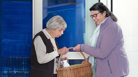 Seniorin hilft älteren Dame beim Einkaufen mit Einkaufskorb